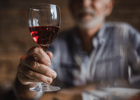Homem segurando uma taça de vinho.