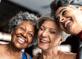 3 mulheres de maior de idade rindo e se abraçando.